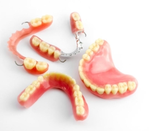 Collection of upper & lower full dentures and two lower partial dentures, one metal cast & the other acrylic