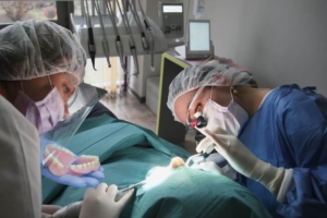 Oral surgeon with assistants extracting a patient's teeth, with immediate dentures ready to be inserted right away