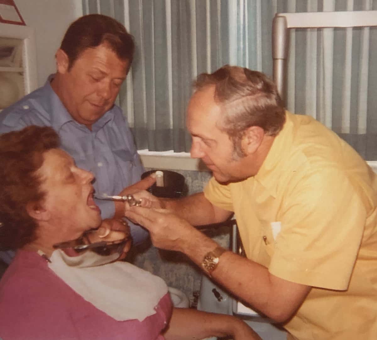 Denturist Joe Schankula doing a procedure on a patient, Tim's maternal grandmother, with Tim's maternal grandfather holding a spit tray underneath her chin
