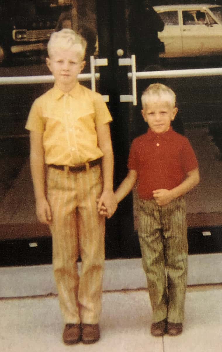 Gary Schankula holding hands and posing with his little brother, Tim, in front of the school doors on Tim's first day of kindergarten