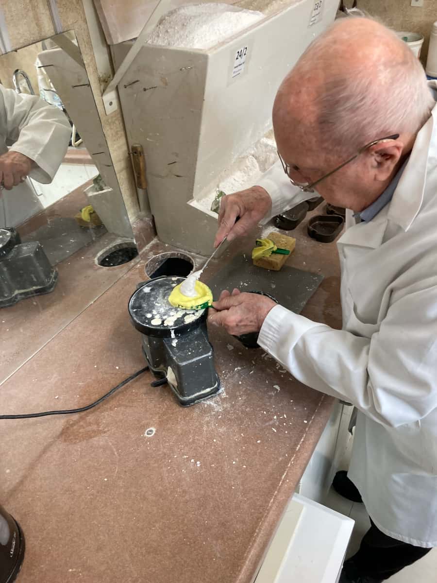 Joe Schankula at 91 using a dental vibrator to pour up a denture model in a patient's impression tray
