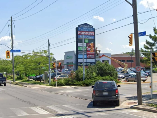 A car turning into Grantham Shopping Plaza from Scott St., showing Sobeys Supermarket and huge pylon with merchant signs