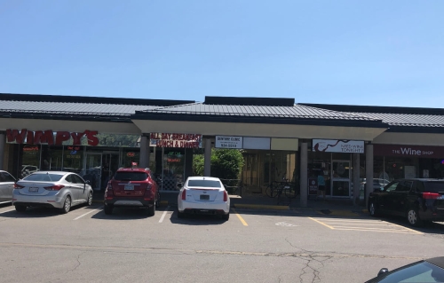 04-Widest shot from left to right: Wimpy's Diner, garden alleyway to Grantham Denture Clinic, and The Wine Shop, with some parked cars in front