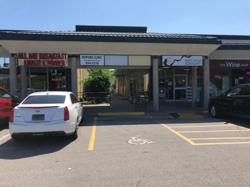 05-Entrance to the garden alleyway to Grantham Denture Clinic, with Tim Schankula Denture Clinic sign with phone number and Wimpy's Diner on the left and The Wine Shop on the right, and an empty handicap parking and ramp right in front of the alleyway, wide shot