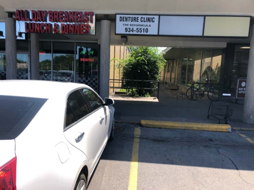Entrance to the garden alleyway to Grantham Denture Clinic, with Tim Schankula Denture Clinic sign with phone number and Wimpy's Diner on the left with its "All Day Breakfast, Lunch  Dinner" sign and a parked car in front of it, closer shot