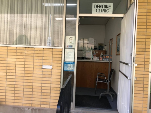 A patient's point of view starting to enter our wide open front door, looking into our reception, showing a coat tree, a chair, and pamphlets on our reception desk countertop